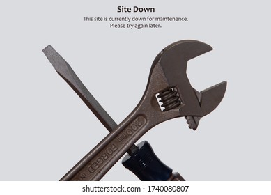 Maintenence photo of an adjustable crescent wrench and a screwdriver against a solid neutral / white background. Landing page photo stating "Site Down", "This site is currently down for maintenence". - Shutterstock ID 1740080807