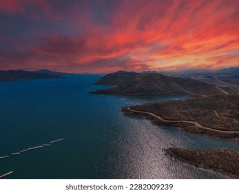 a majestic aerial shot of the vast blue waters of Diamond Valley Lake with gorgeous mountain ranges, lush green trees, red sky and powerful clouds at sunset in Hemet California USA	 - Powered by Shutterstock