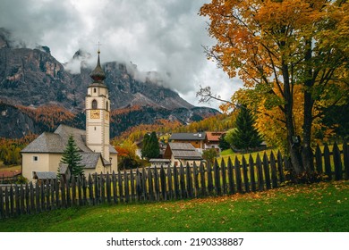 Majestic Autumn Scenery With Colorful Larch Forest On The Cliffs. Charming Alpine Village With Beautiful Church. Great Hiking And Touristic Places, Colfosco, Dolomites, Italy, Europe