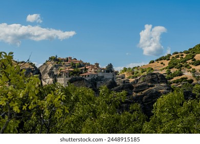 Majestic cliffside monastery with blue skies and green surroundings in Meteora Greece - Powered by Shutterstock