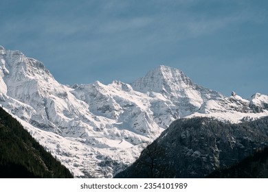 Majestic Dolomites Landscape. Snow-Covered Mountains and Pine Trees in the Italian Alps. A snow covered mountain with pine trees in the foreground. - Powered by Shutterstock