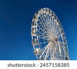 A majestic Ferris wheel stands tall against a clear blue sky. Amusement Park.