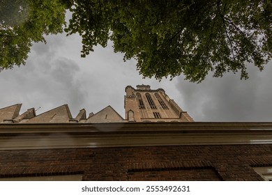 A majestic Gothic church under a dramatic cloudy sky. The intricate brickwork, towering windows, and clock tower reflect its historic architecture and timeless grandeur. - Powered by Shutterstock