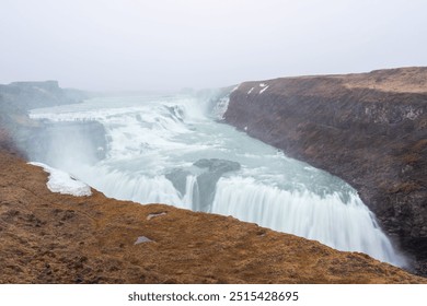 The majestic Gullfoss waterfall in Iceland, formed by the Hvita river cascading down two tiers into a narrow canyon. The powerful water flow and misty spray create a breathtaking sight. - Powered by Shutterstock