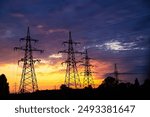 Majestic high-voltage power lines against the backdrop of a beautiful sunset. Metal wires on a high-voltage tower transmit electricity over long distances to cities and villages. Ukraine