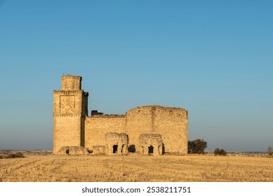 A majestic medieval castle ruins in Barcience (Toledo) rise amidst golden fields, bathed in warm sunlight. The clear blue sky enhances the serene landscape of rural Spain. - Powered by Shutterstock