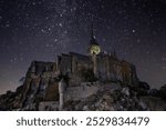 Majestic Mont Saint Michel at night, illuminated under a starry sky. This iconic French landmark captures medieval charm and mystical beauty, perfect for travel and heritage themes.