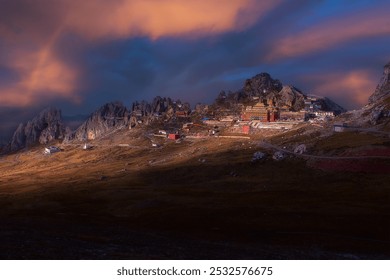 Majestic mountain range with rugged peaks, vibrant structures nestled against slopes, under a dreamy, glowing sky with warm hues. - Powered by Shutterstock