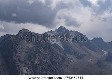 Majestic Mountain Range Under Dramatic Clouds with Glacial Features and Rugged Terrain Captured in a Brooding Atmosphere