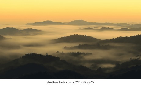 Majestic mountains stand tall against a backdrop of hazy skies and drifting mist. - Powered by Shutterstock