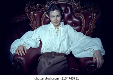 A Majestic Prince Of Elves Sits In A Vintage Armchair In His Magic Castle And Smiles. Fantasy. Fairy Tale, Magic. 