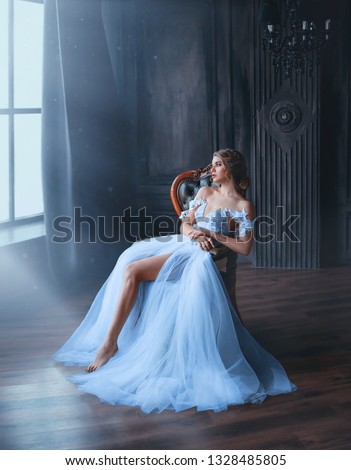 majestic and proud princess girl in white chic oriental blue dress tired sitting on chair, lady shows off her slender leg and waiting for prince, gentle stylish image of graduate 2019. Fine art