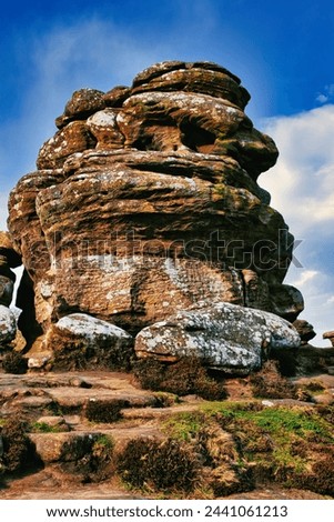 Majestic rock formation under blue sky with clouds, showcasing natural erosion and geological layers at Brimham Rocks, in North Yorkshire