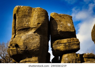 Majestic rock formations against a blue sky with clouds, showcasing natural erosion and geological textures at Brimham Rocks, in North Yorkshire