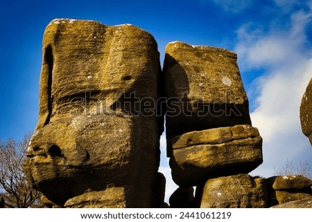 Majestic rock formations against a blue sky with clouds, showcasing natural erosion and geological textures at Brimham Rocks, in North Yorkshire