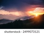 Majestic scene of a heavy downpour illuminated by the rays of the sun. Unique natural phenomenon. Location place Carpathian mountains, Ukraine, Europe. Photo wallpaper. Discovery the beauty of earth.