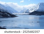 Majestic snow-capped mountains towering over a tranquil lake filled with floating ice in New Zealand. The vast landscape offers a breathtaking view of nature’s raw beauty.