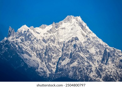 A majestic snow-covered mountain range stretches across the horizon, its peaks gleaming against a brilliant blue sky.
 - Powered by Shutterstock