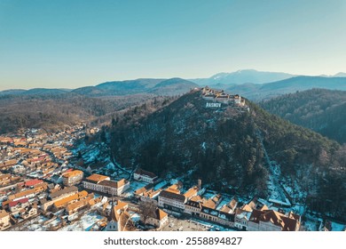 Majestic snow-covered peaks frame the charming town of Rasnov, with its iconic hilltop fortress offering stunning views - Powered by Shutterstock