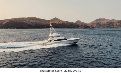 A majestic sport fishing boat sailing through the tranquil waters of a lake situated near a lush mountain range - Powered by Shutterstock