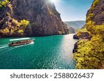 Majestic spring view of Matka Canyon with small cruise boat atd tourists on it. Picturesque morning scene of deep canyon in North Macedonia, Europe. Traveling concept background.