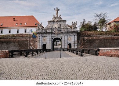 Majestic stone archway of historic fortress, adorned with statues and intricate details.Cobblestone path leads to the imposing entrance. Perfect blend of history and architecture.  Alba Iulia, Romania - Powered by Shutterstock