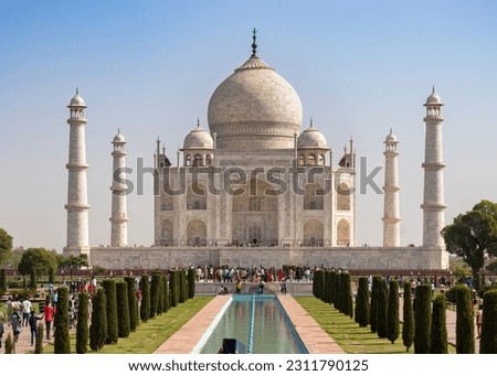 A majestic Tajmahal, one of the world's seven wonders is viewed along with its lush green garden. A clear blue sky adds magnificence to the white marble of the beautiful architectural structure.