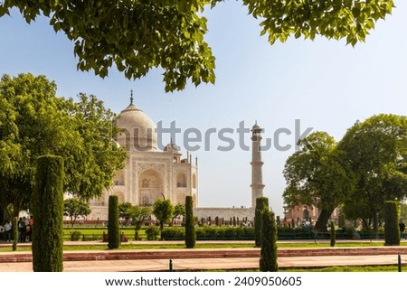 A majestic Tajmahal, one of the world's seven wonders is viewed along with its minaret and lush green garden. A clear blue sky adds magnificence to the white marble of the beautiful structure.