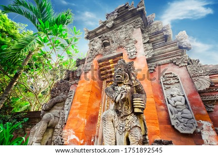 Majestic and tall rock statues Barong Lion Guard near shrine walls lit by sunshine at sunny day, Gunung Kawi Temple Complex, Bali, Indonesia. Balinese mythological creature, made of volcanic rock