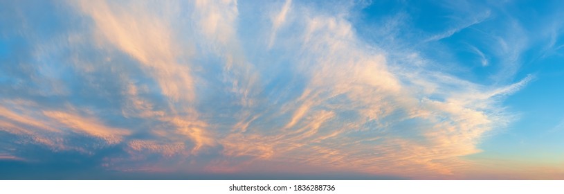 Majestic vanilla sky at evening. Azure sunset heaven with golden pink cirrus clouds over the horizon. Panoramic shot of pastel colored skyscape. Beauty in nature.