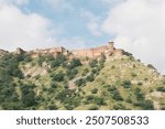 A majestic view of the Amber Fort in Jaipur, India, showcasing its imposing sandstone and marble structure, surrounded by rugged hills and reflecting the grandeur of Rajput architecture