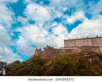 Majestic view of Edinburgh Castle, Scotland, set against dramatic sky. Historic stone fortress rises above lush greenery, capturing essence of Scotland’s heritage ; travelers and history enthusiasts - Powered by Shutterstock