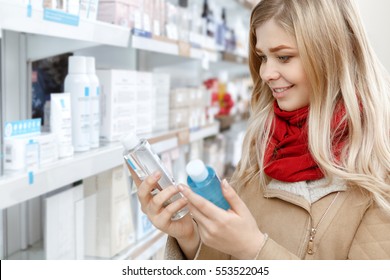 Major Choice. Shot Of A Beautiful Cheerful Female Customer Choosing Between Two Products At The Beauty Store Female Holding Two Bottles Consumer Shopper Buyer Choosing Choice Industry Concept