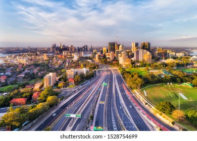 Major Motorway In Sydney City Goring Through North Sydney To The Sydney Harbour Bridge Seen From Above With Skyline Of High-rise Towers And City Architecture.