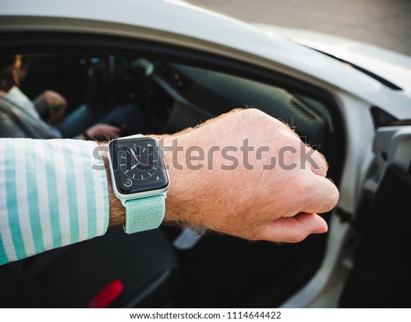 MAJORCA, SPAIN - MAY\
10, 2018: Man checking time on Apple Watch before entering car -\
pov black and white
