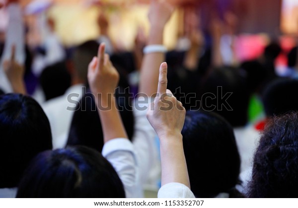 Majority of volunteer\
people reacting to the question by raising their index finger\
together as teamwork for unity and unanimous agreement and\
collaboration in the\
classroom