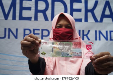 MAKASSAR, INDONESIA - AUGUST 18 2020: A resident shows a new bank note worth 75,000 rupiah