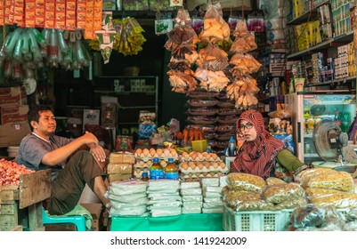 Makassar, Sulawesi, Indonesia - February 28, 2019: Terong Street Market. Closeup of well-stocked grocery booth with couple vendors. Several colors on a darker background.