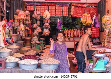 Makassar, Sulawesi, Indonesia - February 28, 2019: Terong Street Market. Woman and half-naked young man stand in their booth selling muts and seeds.