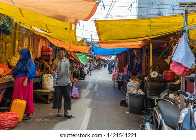 Makassar, Sulawesi, Indonesia - February 28, 2019: Terong Street Market. Shot in the middle of the street with a line of booths on both sides. Shoppers doing their purchases. Yellow tarps.