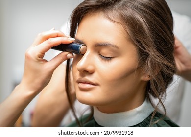 Make up artist contouring the face of a young woman with cream blush close up