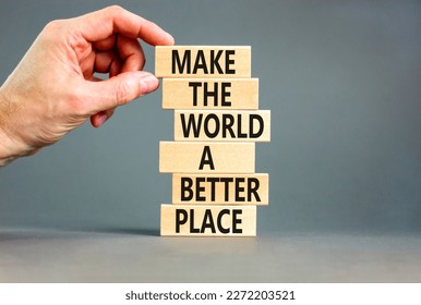 Make a better world symbol. Concept words Make the world a better place on wooden blocks. Beautiful grey table grey background. Businessman hand. Business make a better world concept. Copy space.