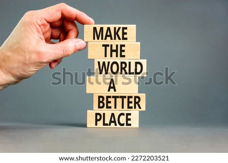 Make a better world symbol. Concept words Make the world a better place on wooden blocks. Beautiful grey table grey background. Businessman hand. Business make a better world concept. Copy space.