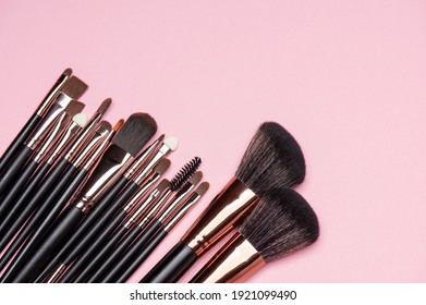 Make up brush sets arranged on pink background, top view with copy space. Cosmetics products.