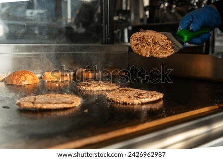 Make burgers on the grill restaurant. Burgers cooking on a gas grill. Chef preparing burgers at the kitchen grill stove. The cook prepare beef for cheese burger in fast food restaurant. make a burger.