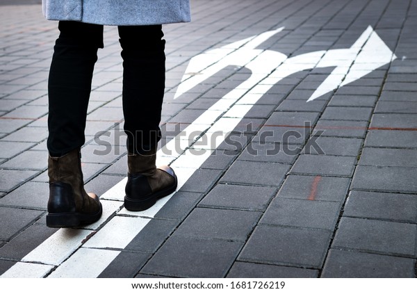 Make choice which way to go.\
Decision concept with directional arrow sign on road and\
woman