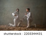 To make contact, the concept of a relationship with a partner. A man and a woman in retrofuturism space suits are sitting on the sand