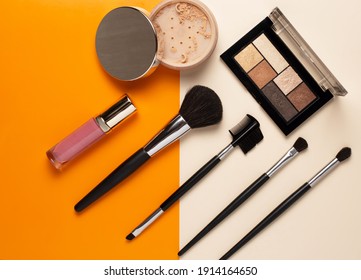 make up cosmetics, powder with various brushes and lipstick. colored background. copy space. flat lay.