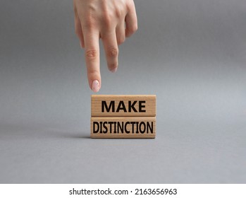 Make distinction symbol. Concept words make distinction on wooden blocks. Beautiful grey background. Businessman hand. Business and make distinction concept. Copy space.