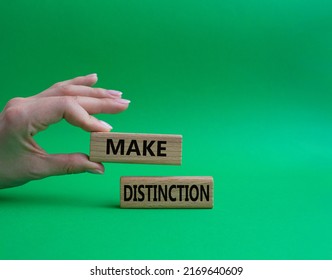 Make distinction symbol. Concept words make distinction on wooden blocks. Beautiful green background. Businessman hand. Business and make distinction concept. Copy space.